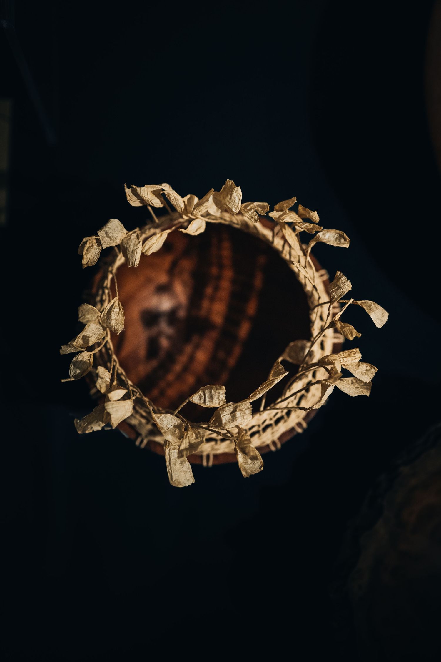 Ornate gold floral frame with a circular mirror against a dark background in dramatic lighting.