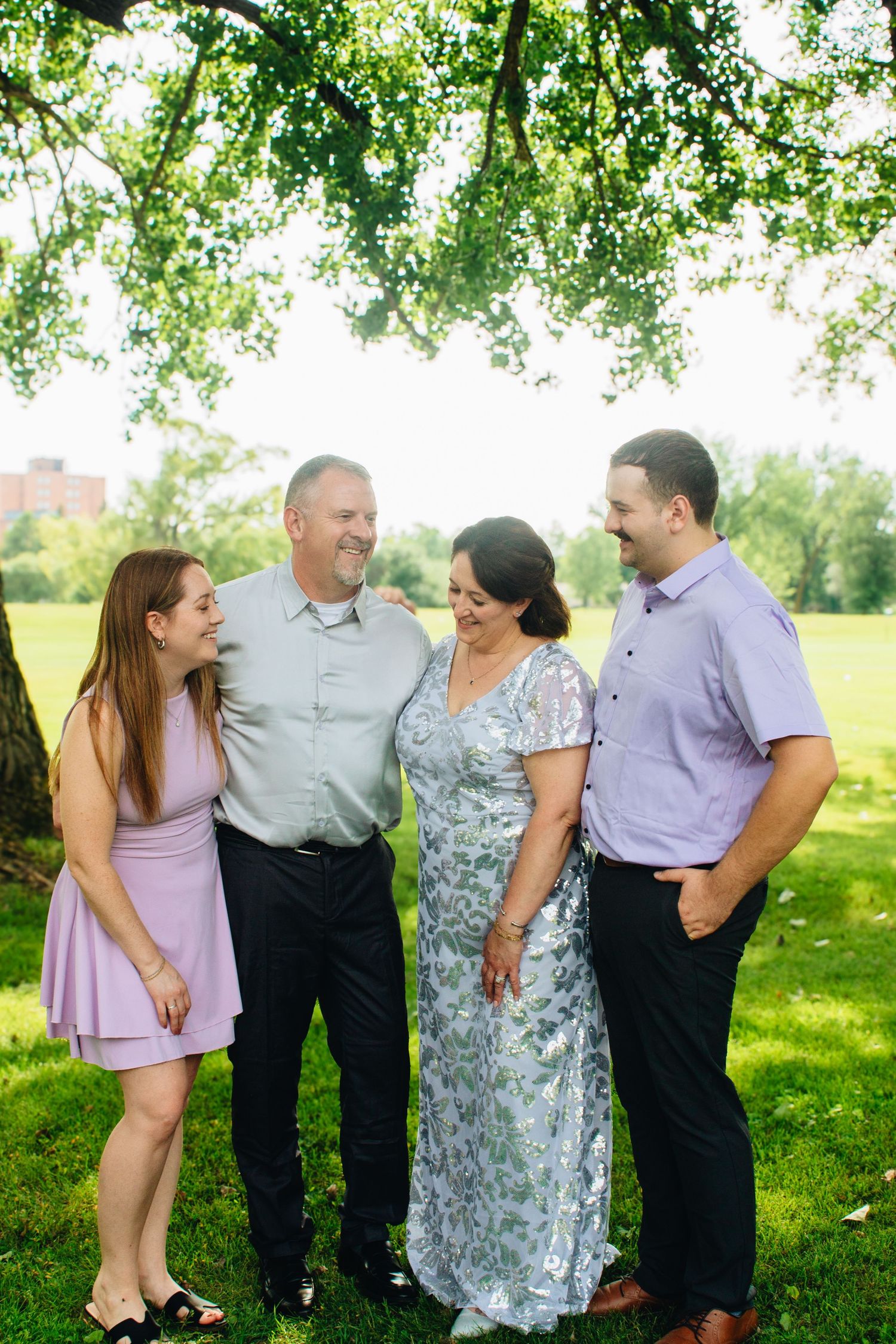 Extended family members gather for casual outdoor portraits in a park setting.