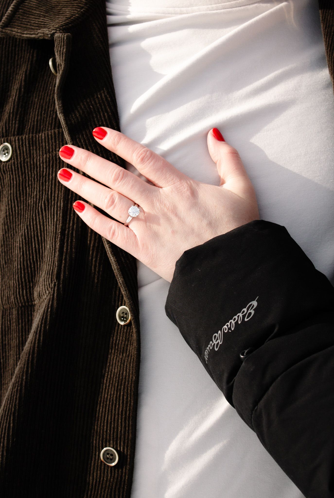 Close-up of hands with red nail polish against white fabric.