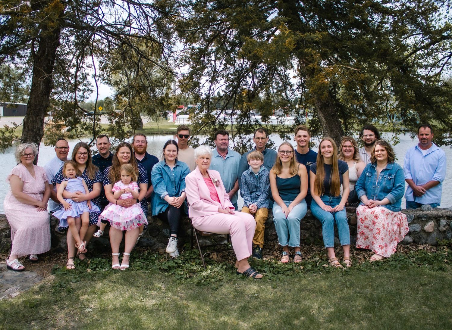 Large family group sits together on grass for a casual outdoor portrait session.
