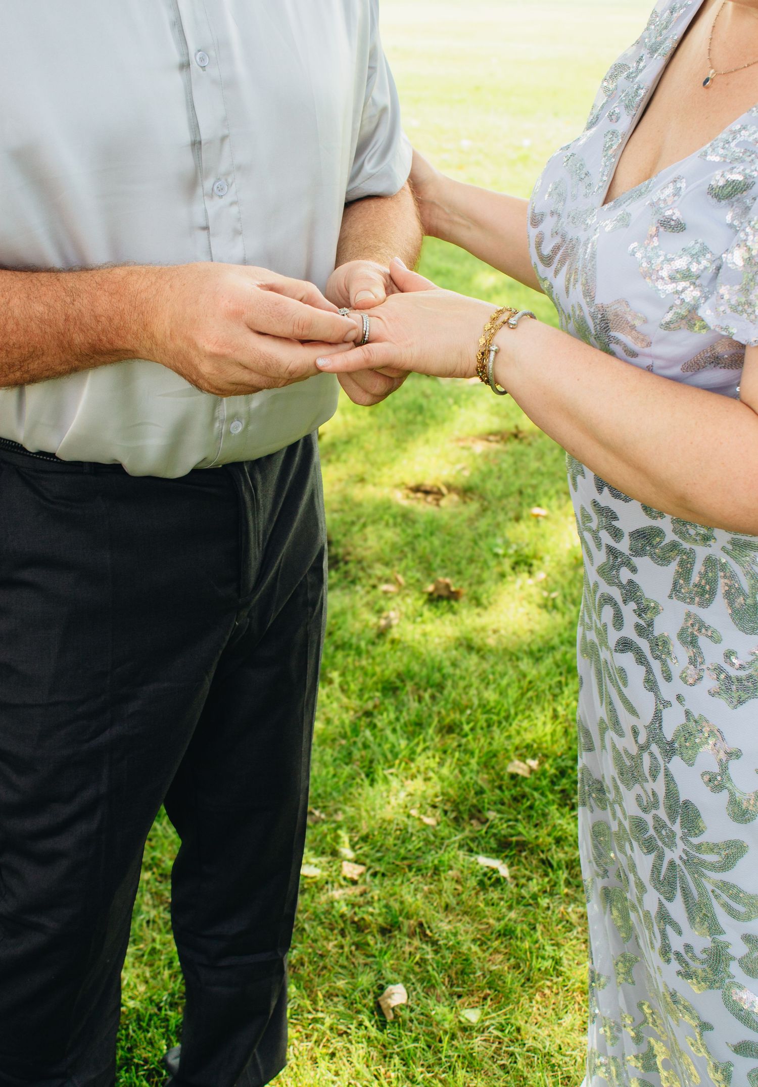 Detail shots of hands exchanging rings during an outdoor ceremony.