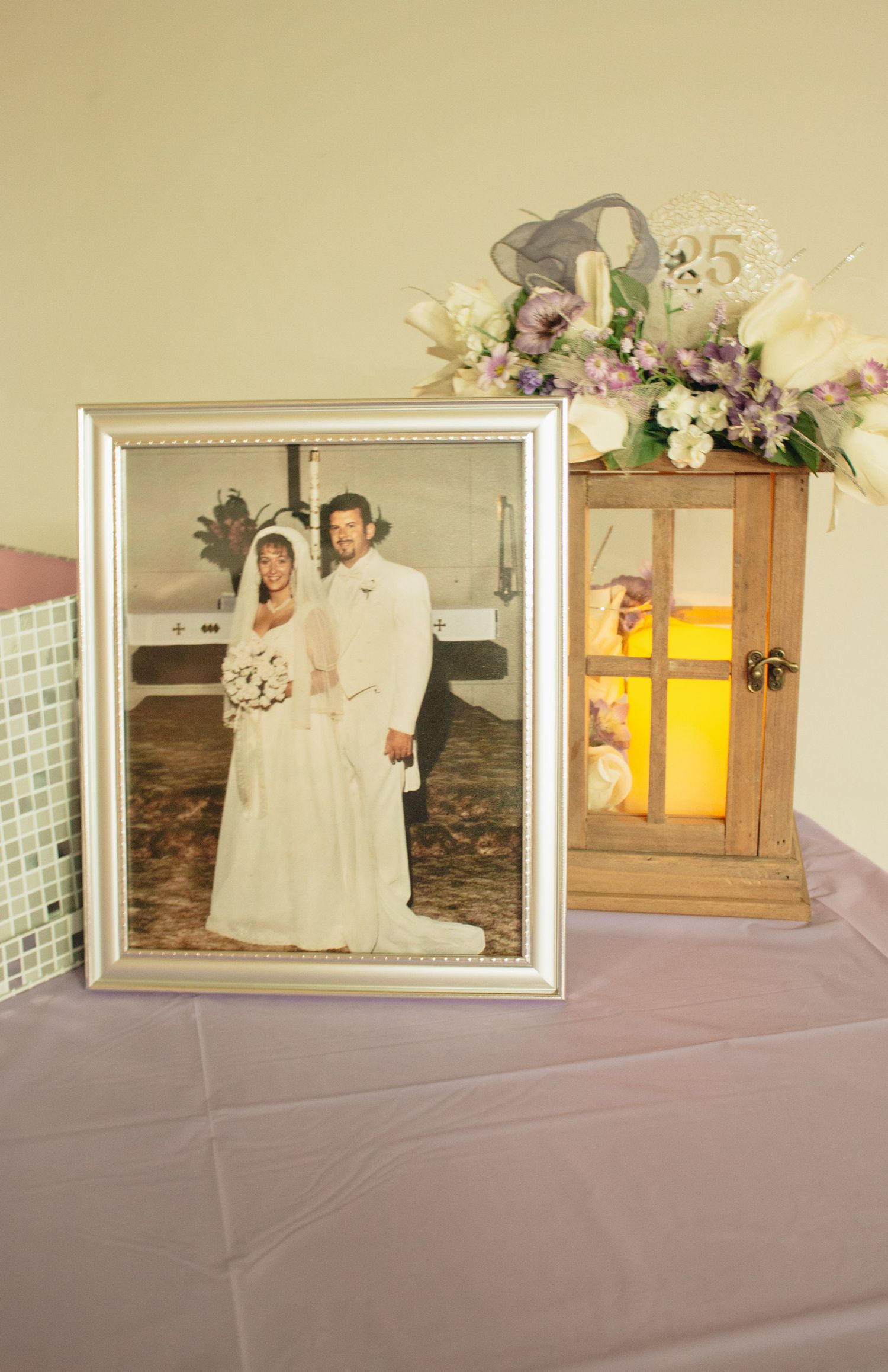 Wedding photos displayed in white frames on a purple tablecloth.