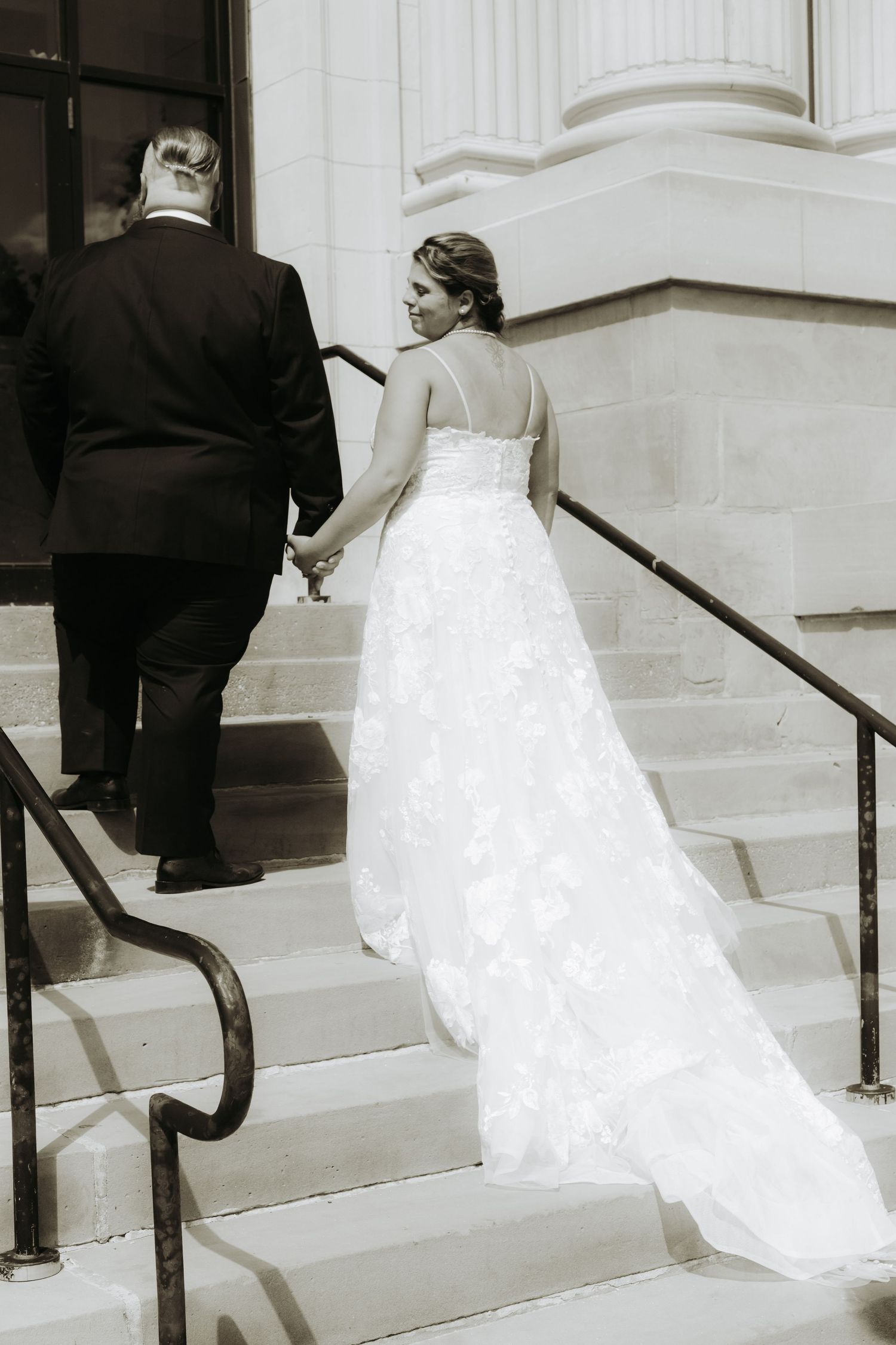 Black and white sequence of a bride in a lace gown ascending stone steps.