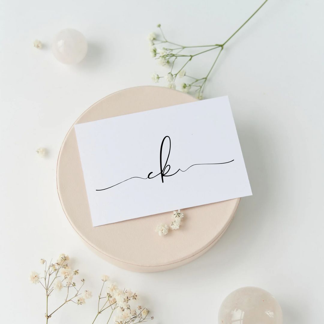 Minimalist place card settings with baby's breath flowers on cream colored plates against a white background.