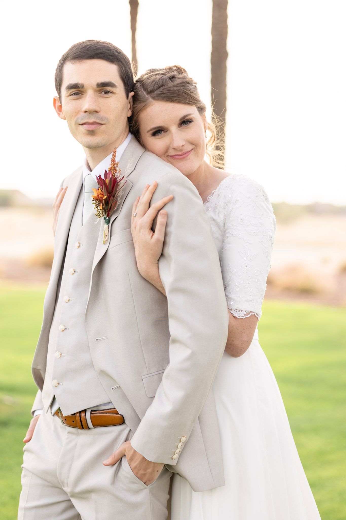 Wedding party poses outdoors with bridesmaids in burgundy dresses and groomsmen in light suits.