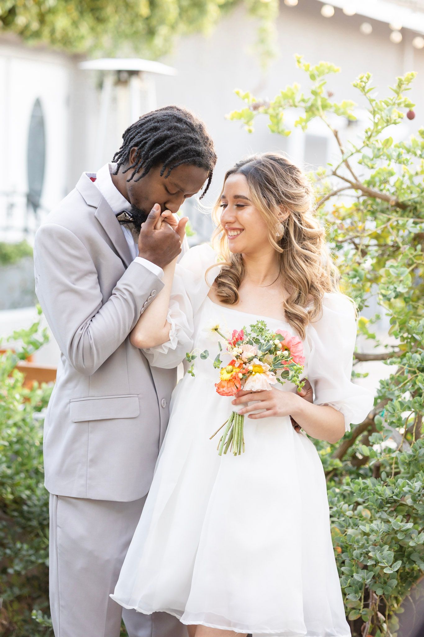 Garden wedding portraits with couple sharing intimate moments near blooming flowers.