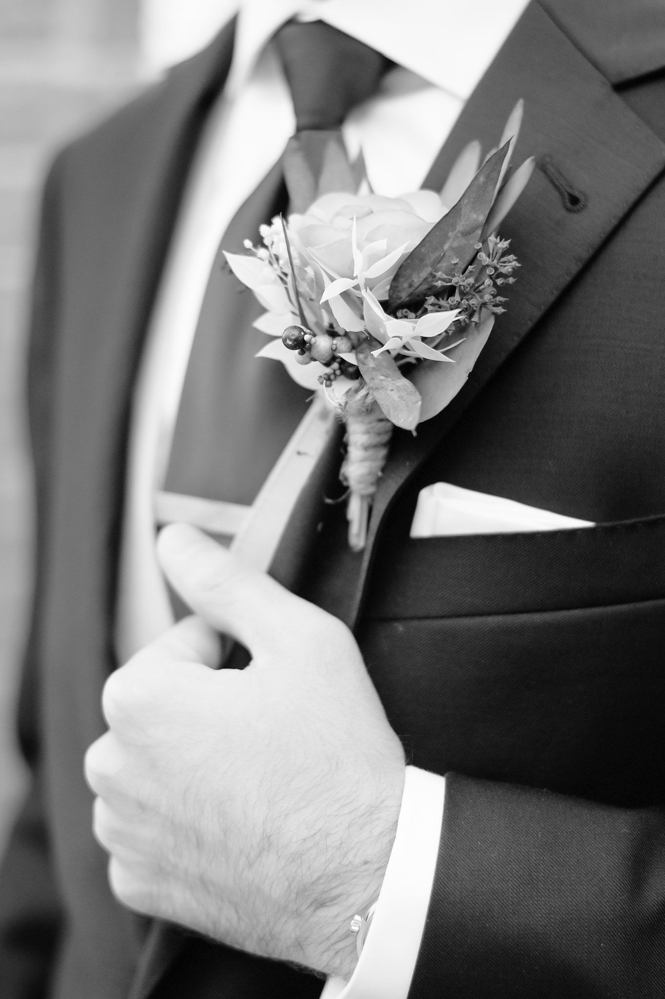 Black and white detail shots of boutonnieres being pinned on formal suits.