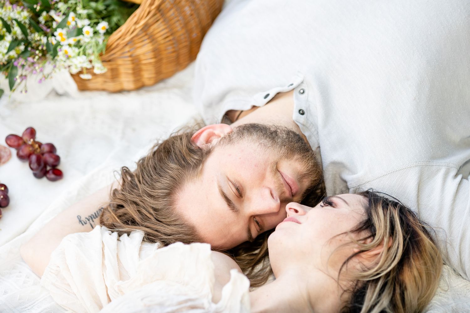 Dreamy boudoir photography with soft white linens and floral accents.