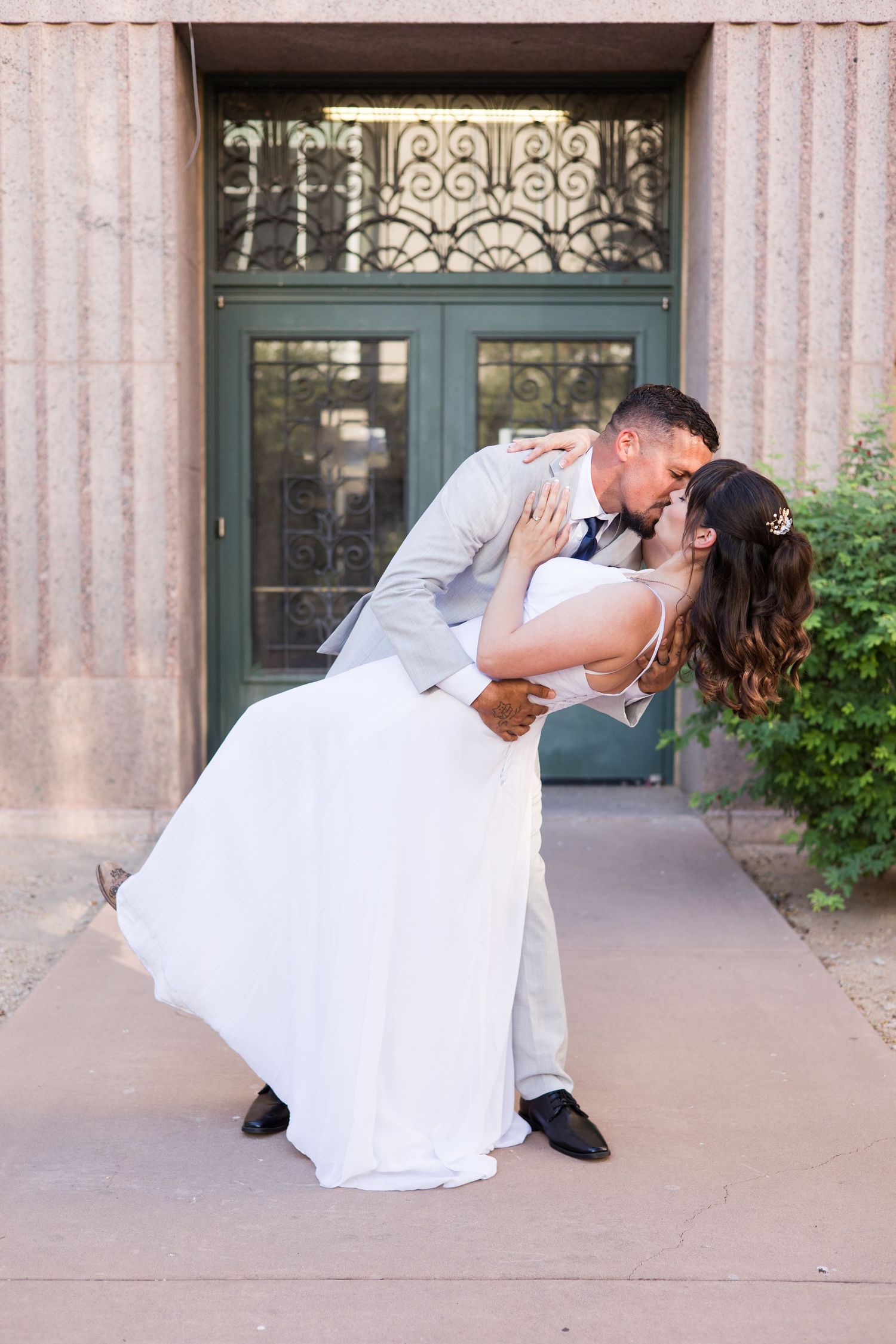 Romantic dip poses by newlyweds in front of an elegant building entrance.