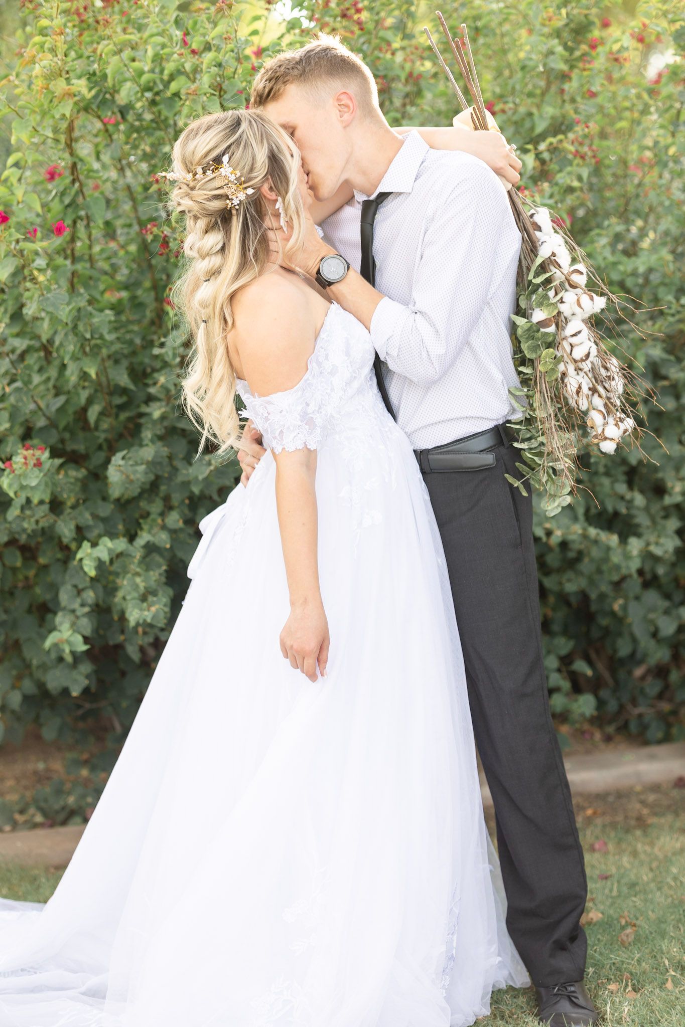 Wedding couple embracing in a garden setting with lush greenery.
