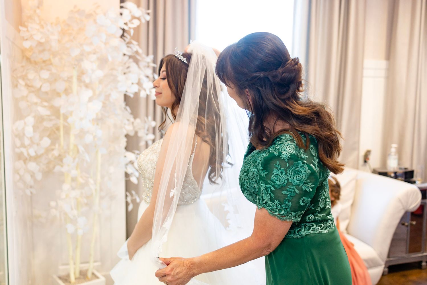 Candid wedding preparation moments with bride and bridesmaid in emerald green.