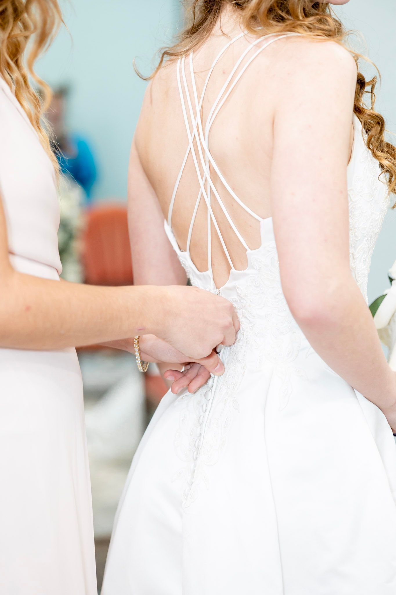 Row of white bridesmaid dresses showing intricate back details and strappy designs.