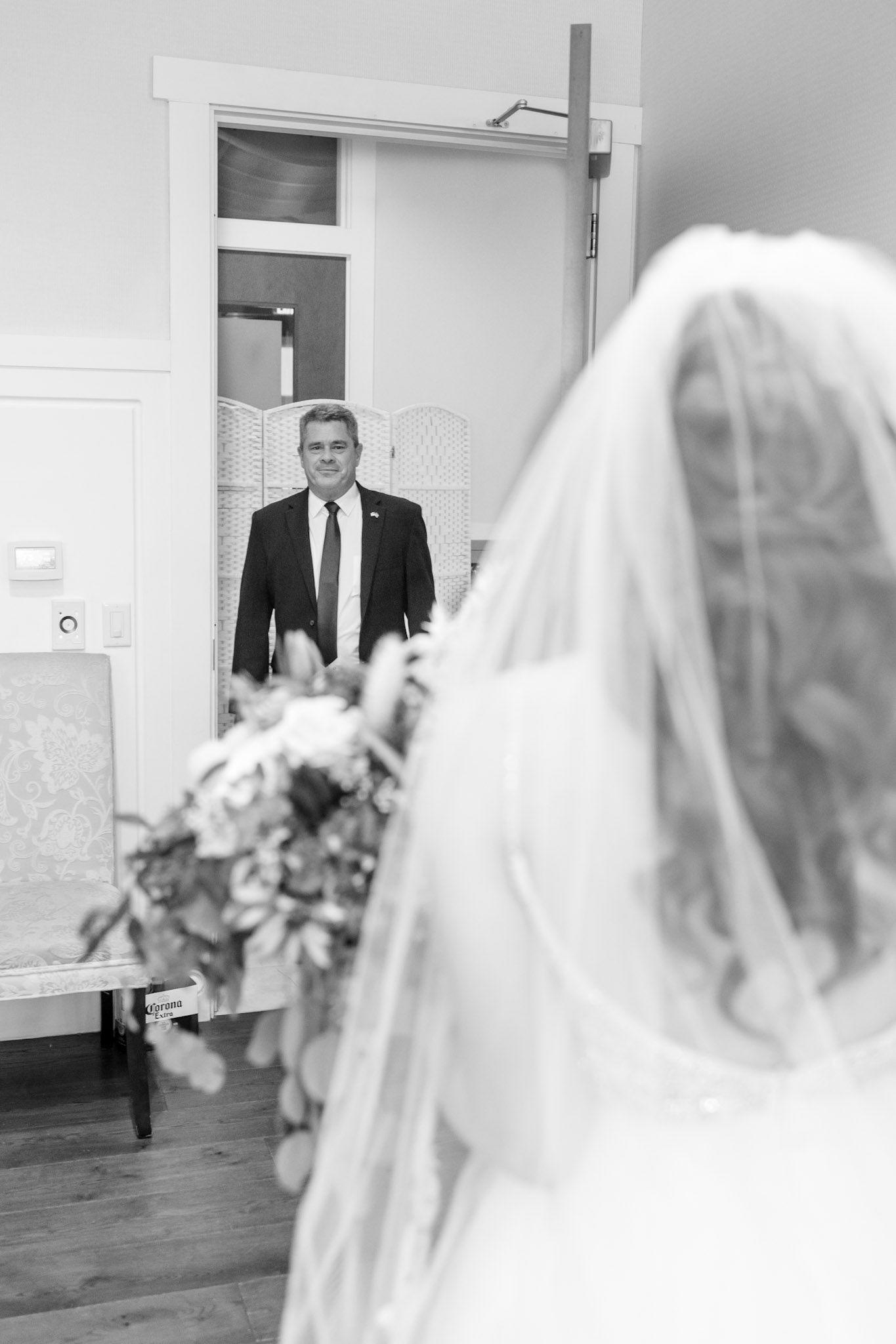 Black and white first look moment between bride in veil and suited figure.