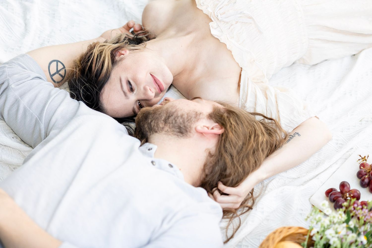 Dreamy couple's portrait session on white blanket with fresh fruit and romantic styling.