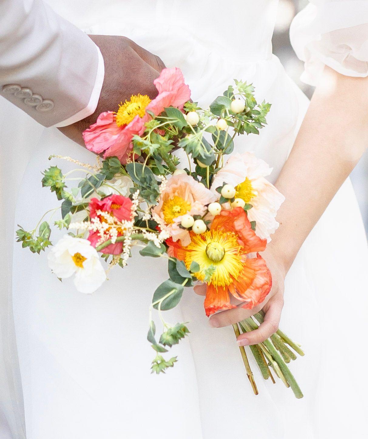 Close-up shots of colorful wedding bouquet with poppies, daisies and greenery.