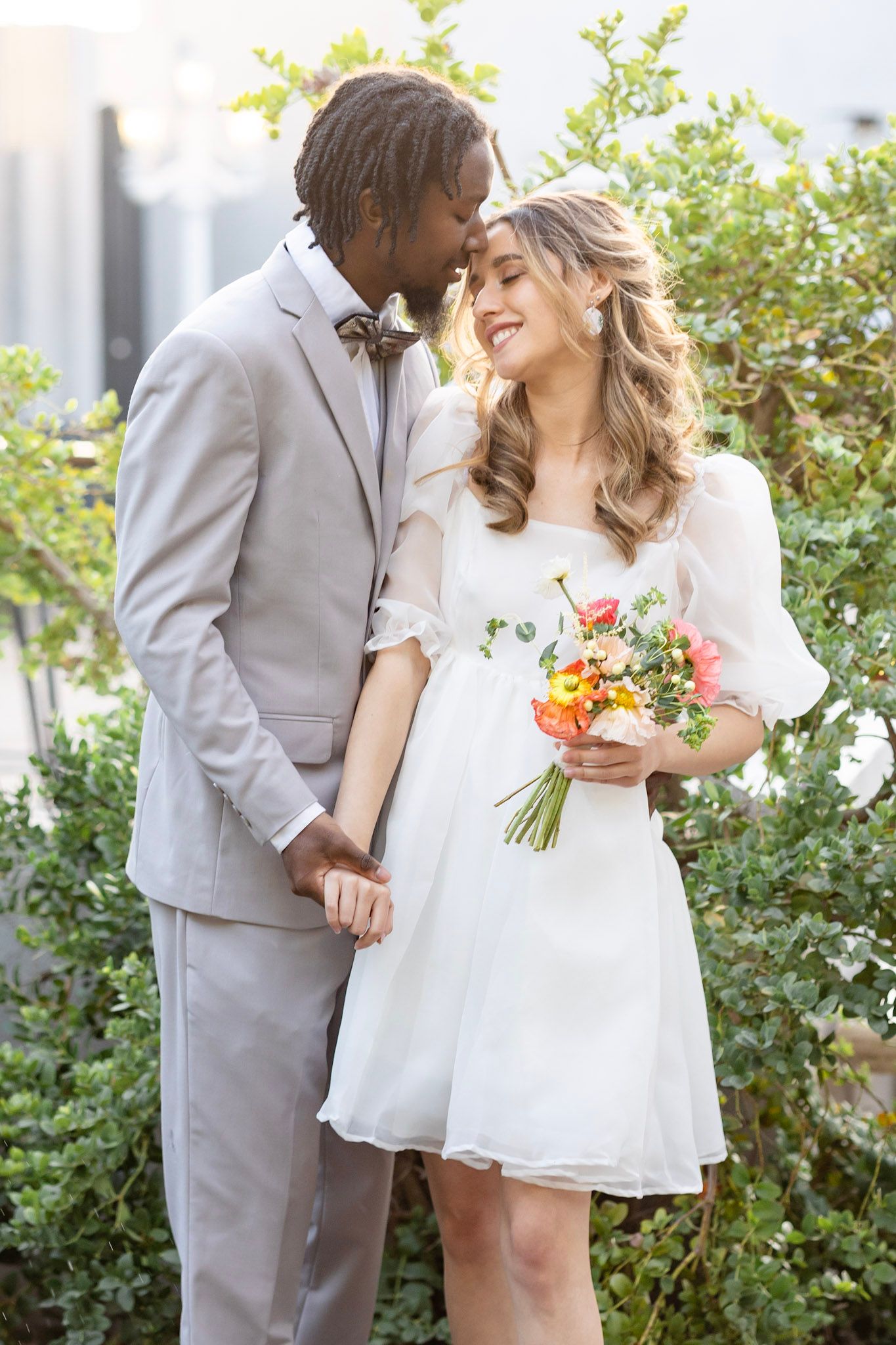 Romantic garden wedding photos with couple in white dress and light gray suit.