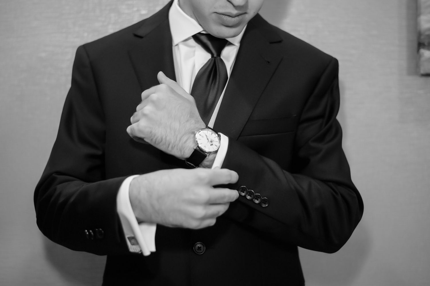 Close-up shots of a groom adjusting his tie and cufflinks before the ceremony.