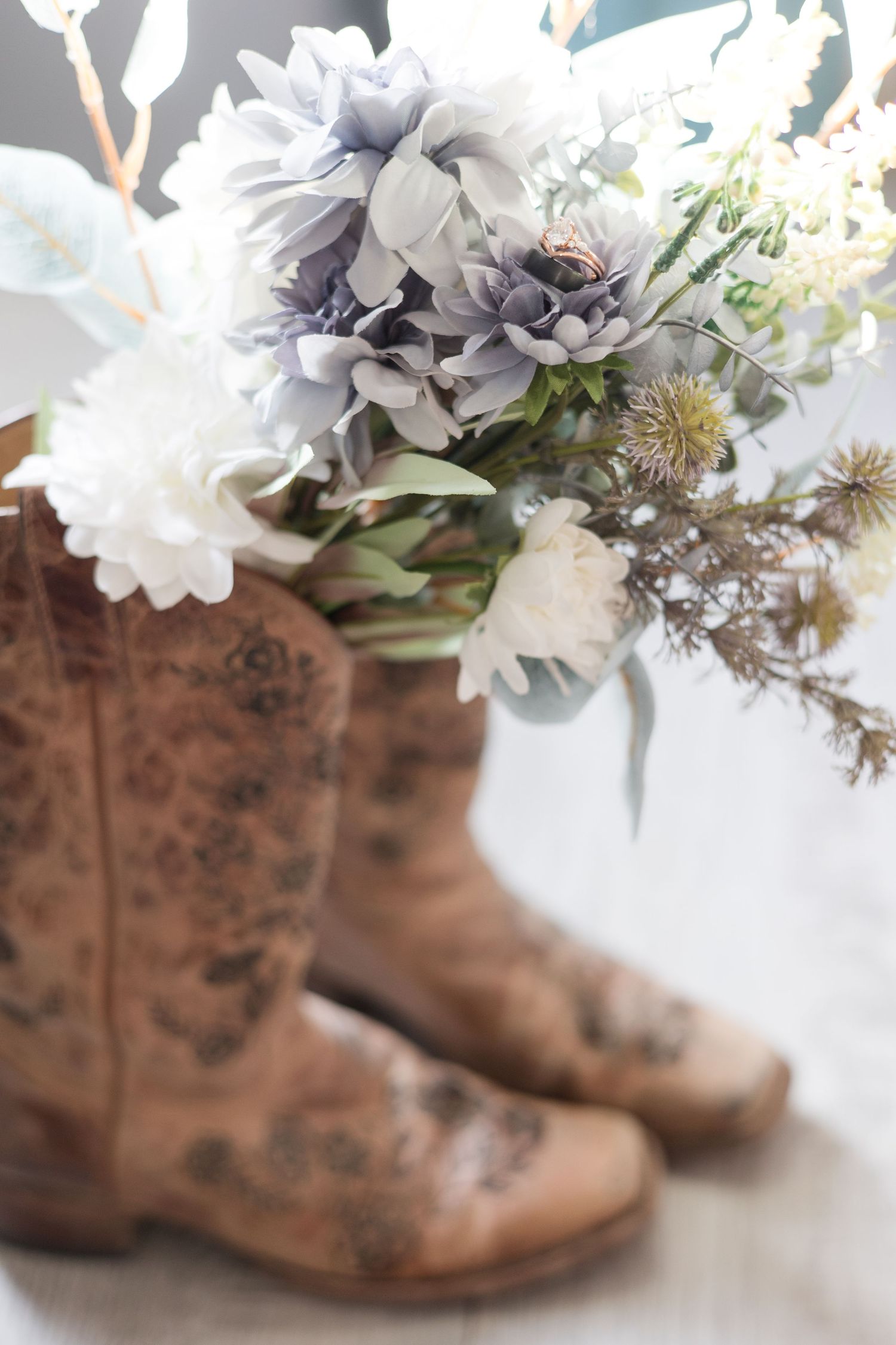 Rustic brown boots decorated with white and grey flowers create a charming vintage display.