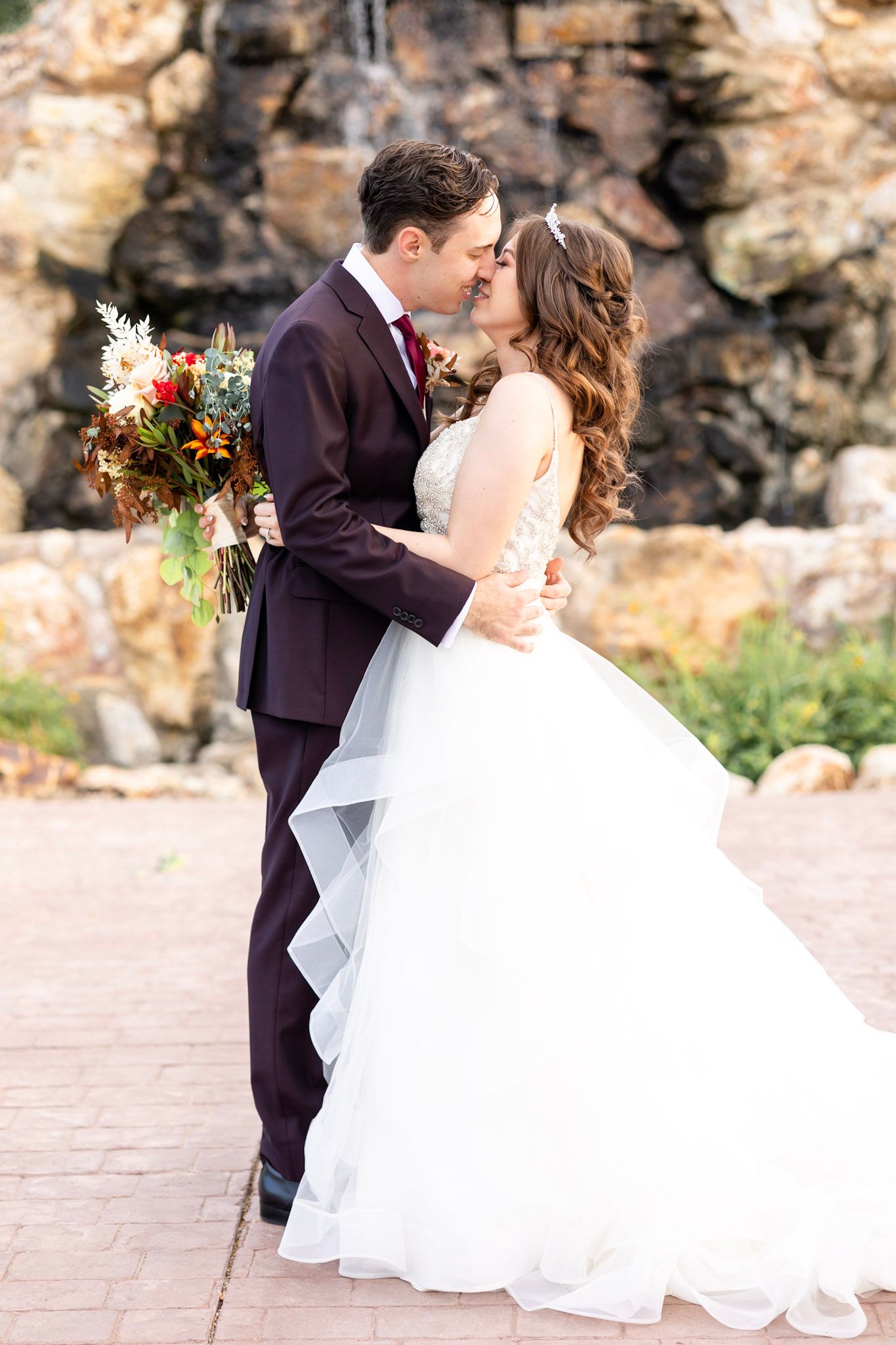 Romantic wedding couple shares intimate moments against rustic stone backdrop.