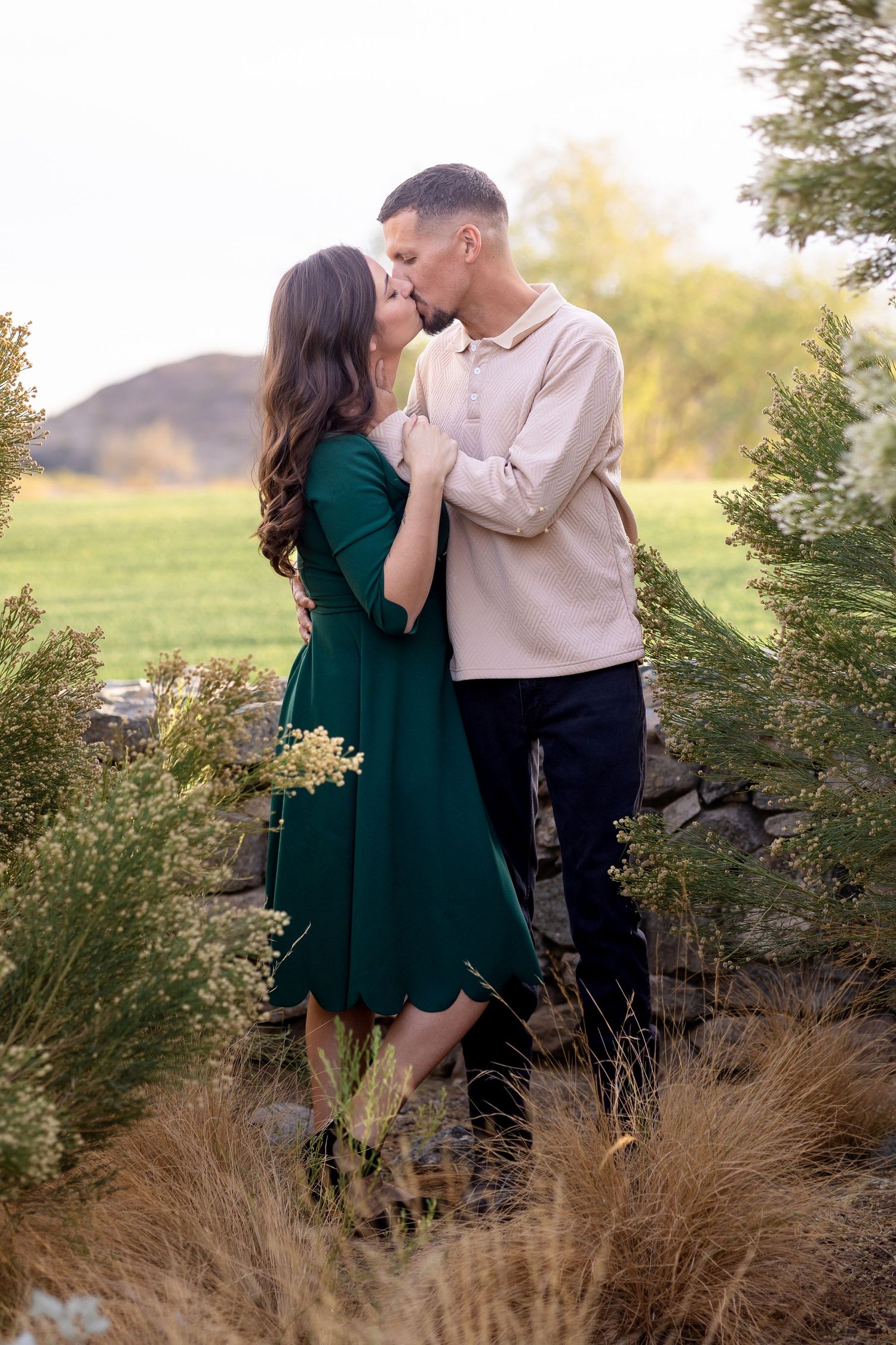 Golden hour engagement session among desert brush with couple in formal attire.