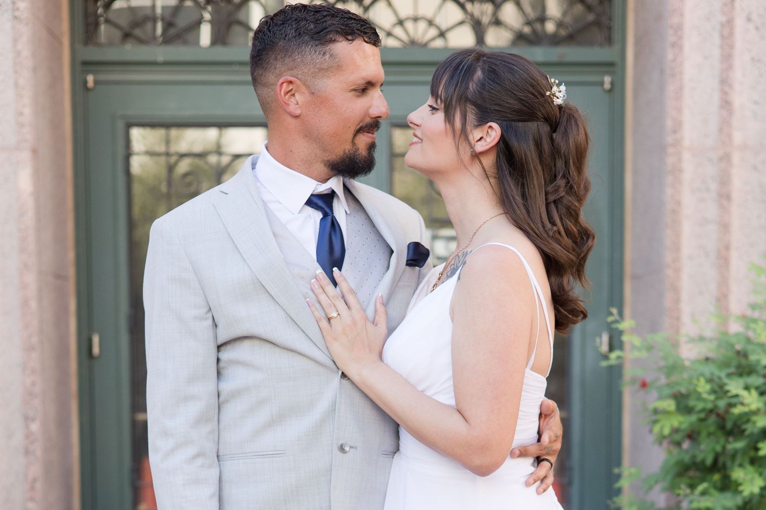 Wedding couple embraces in front of a classic building with columns.
