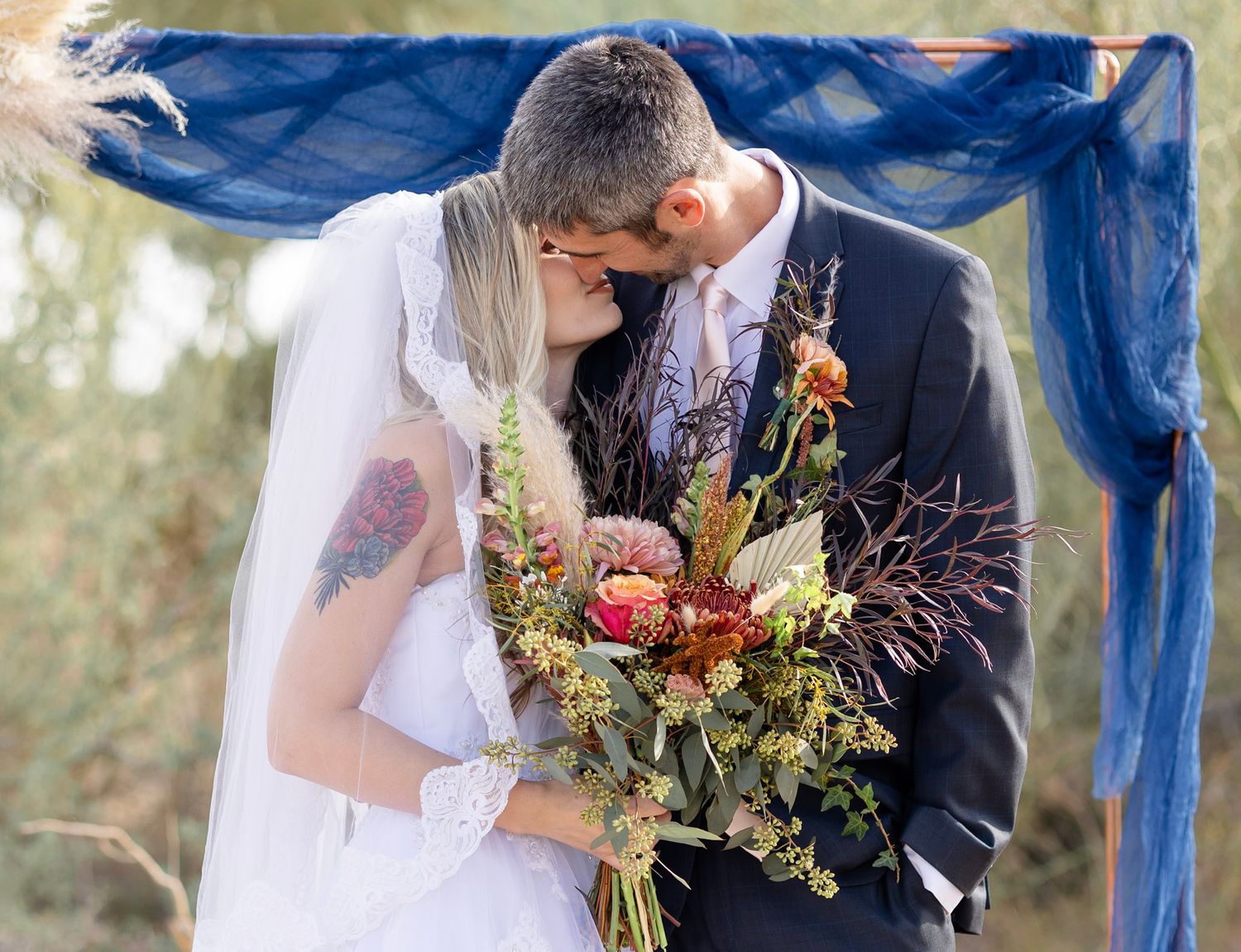 Wedding portraits with navy blue fabric backdrop and autumn-colored floral arrangements.
