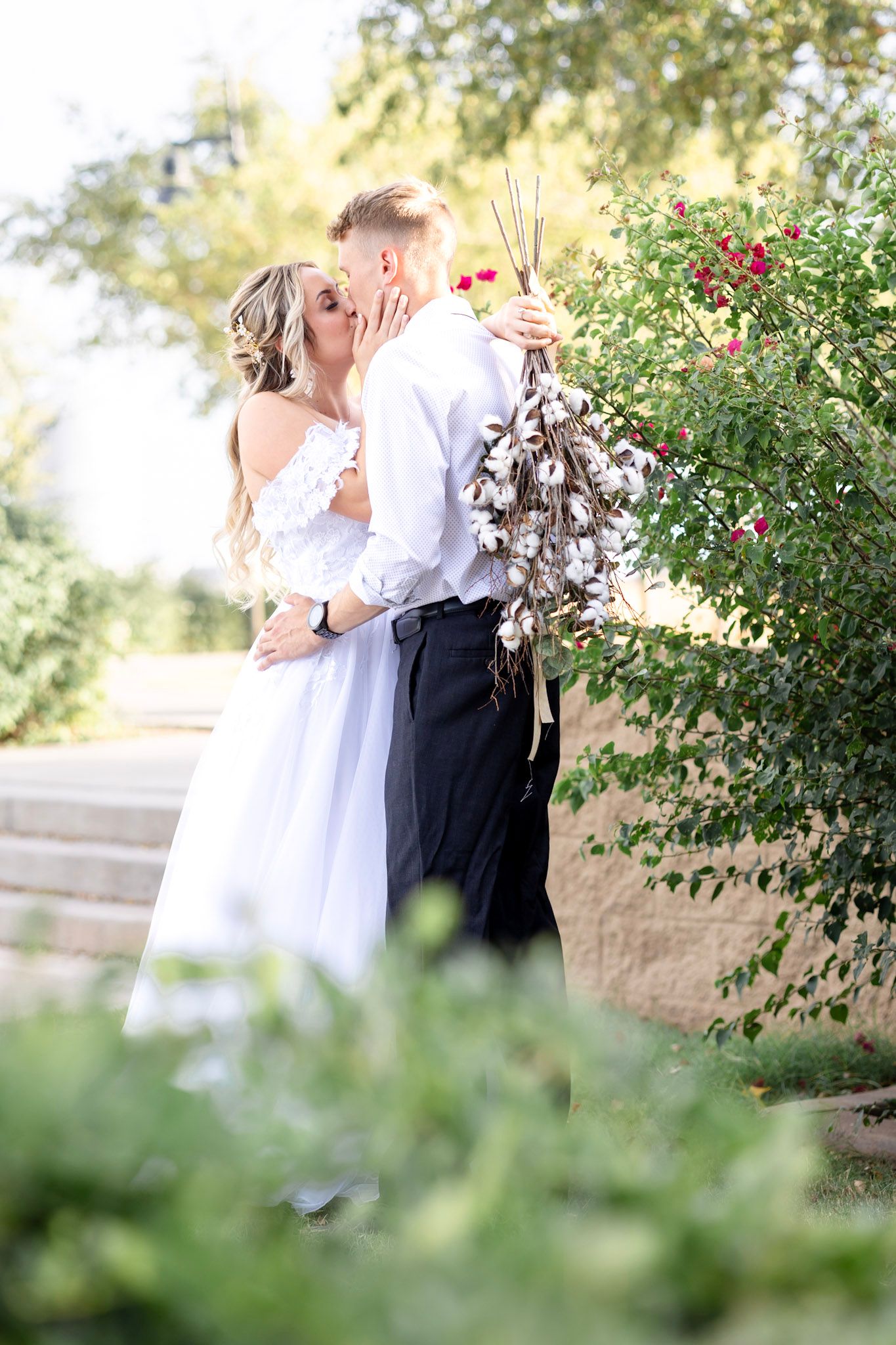 Romantic garden wedding portraits with blooming rose bushes in the background.