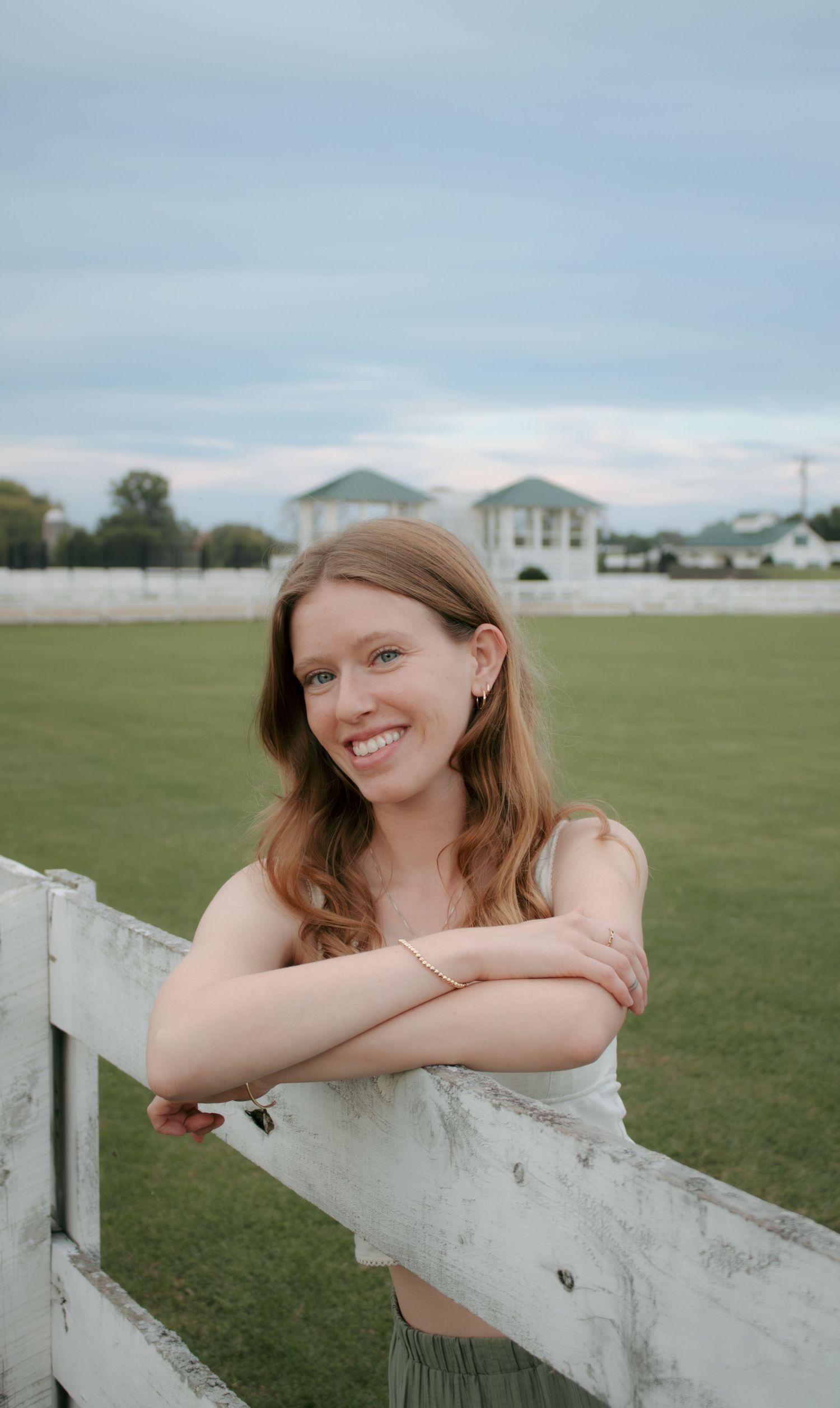 A series of four connected photos showing someone leaning on a white fence post in a grassy field on an overcast day.