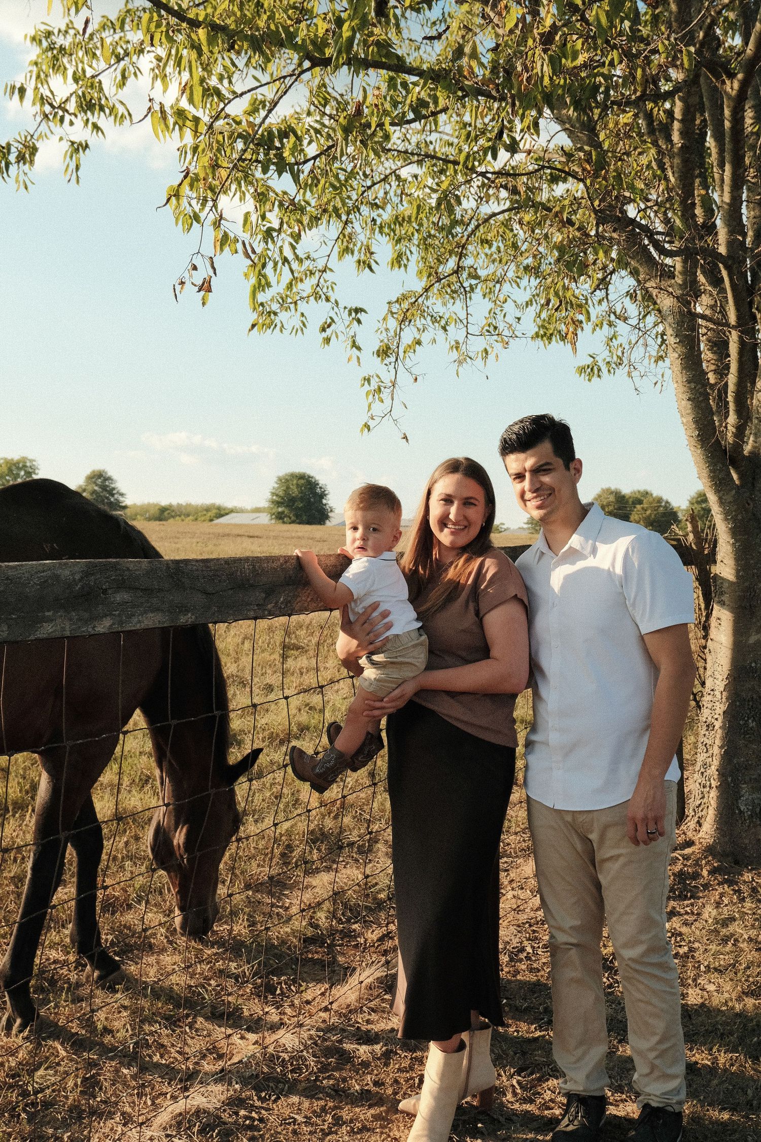 Family poses together under autumn trees during outdoor photo session.
