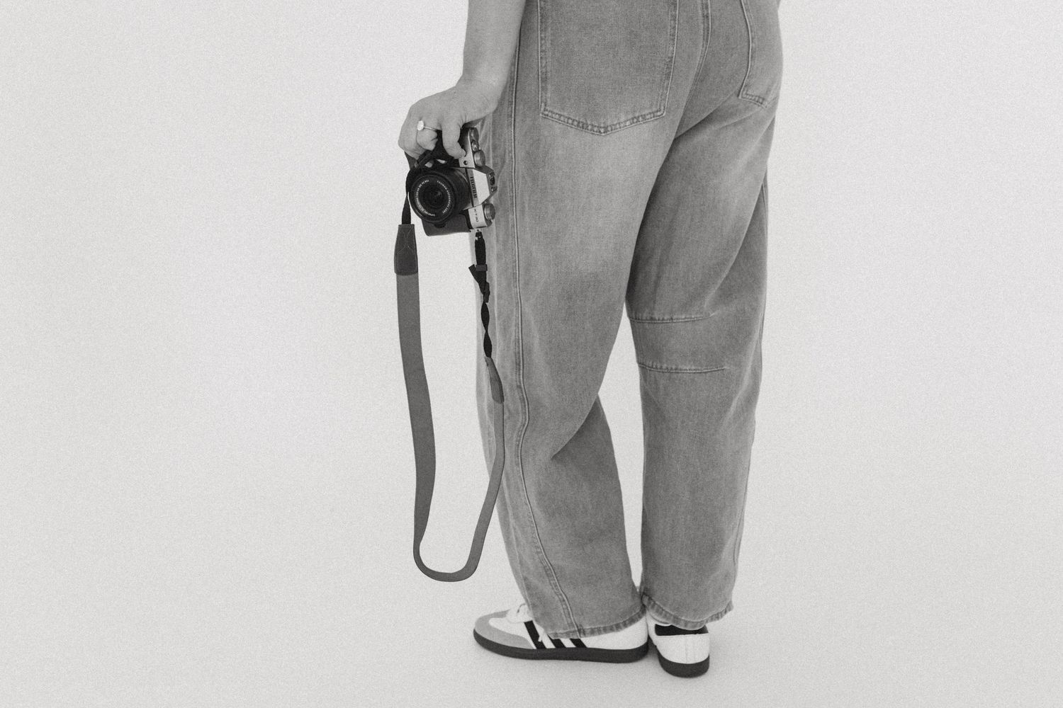 Photographer's legs and camera equipment shown against white studio background.