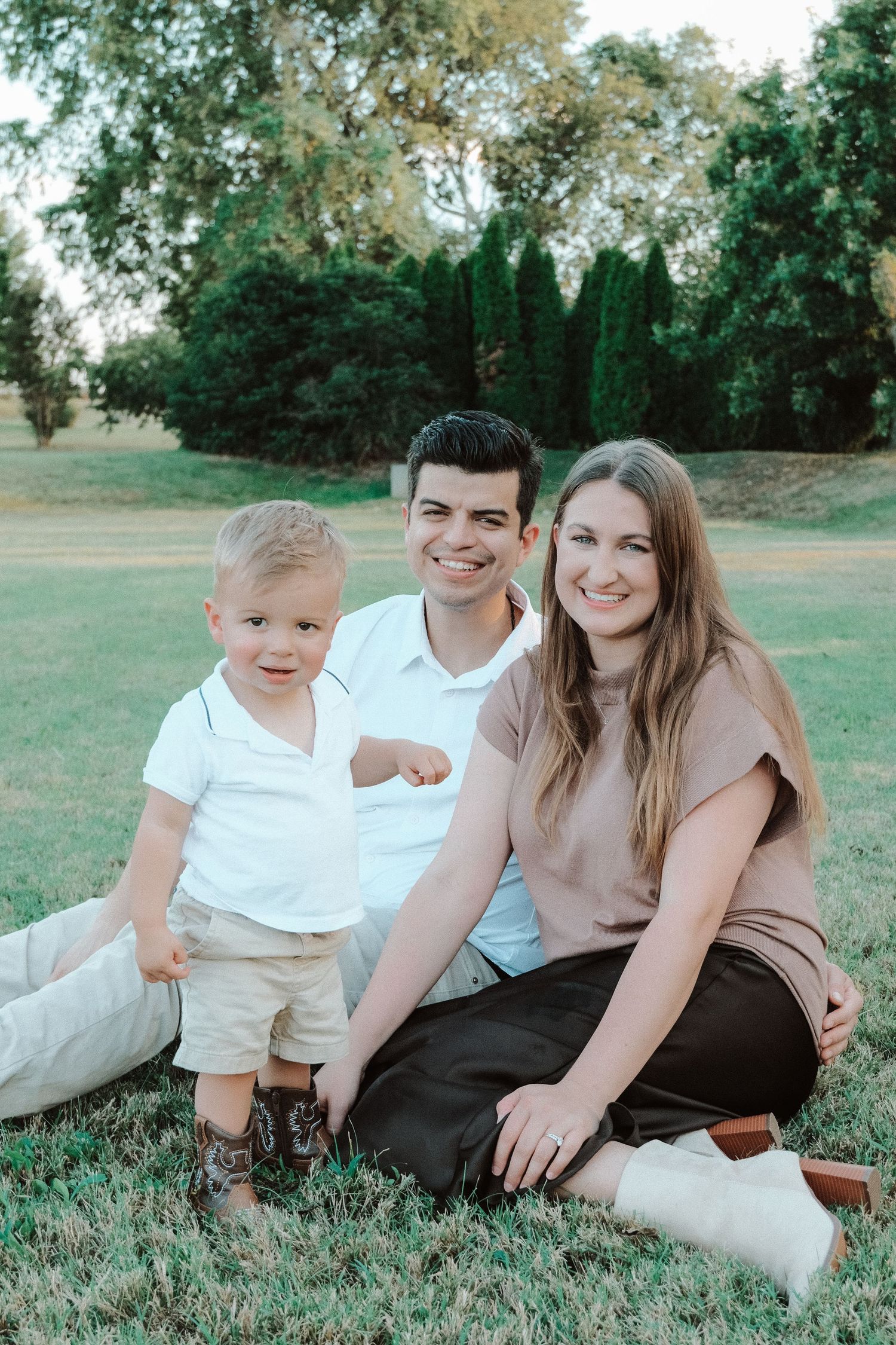 Family relaxes together on grass during outdoor portrait session.