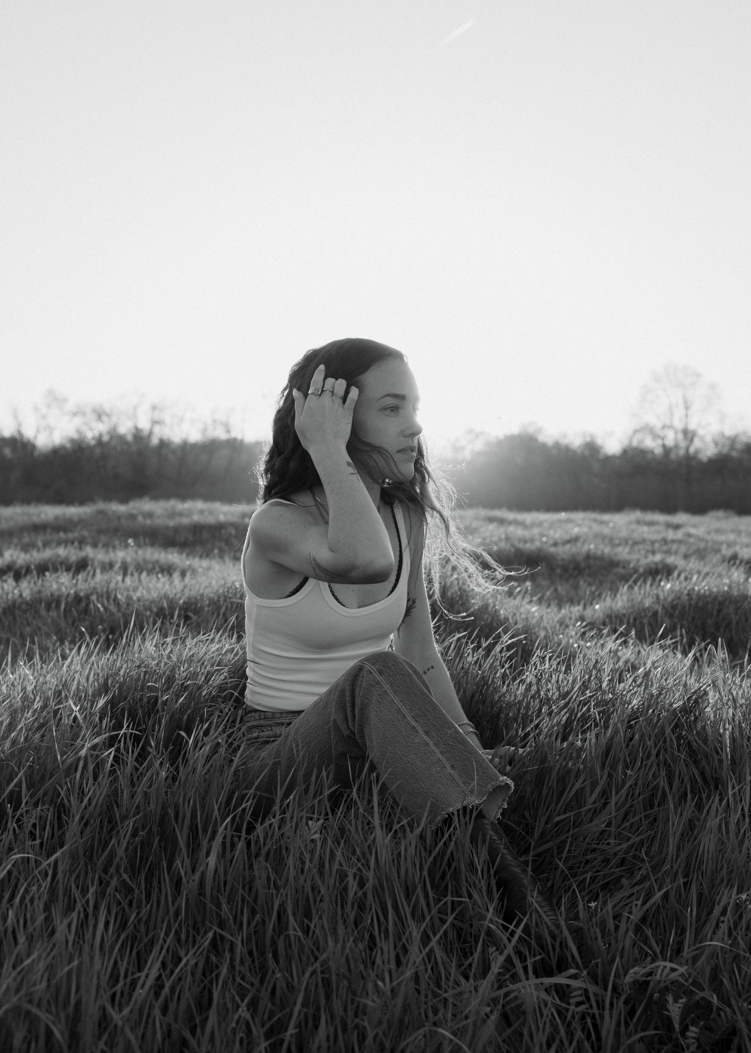 A black and white photo sequence shows someone lying down in tall grass at sunset, creating a dreamy silhouette effect.