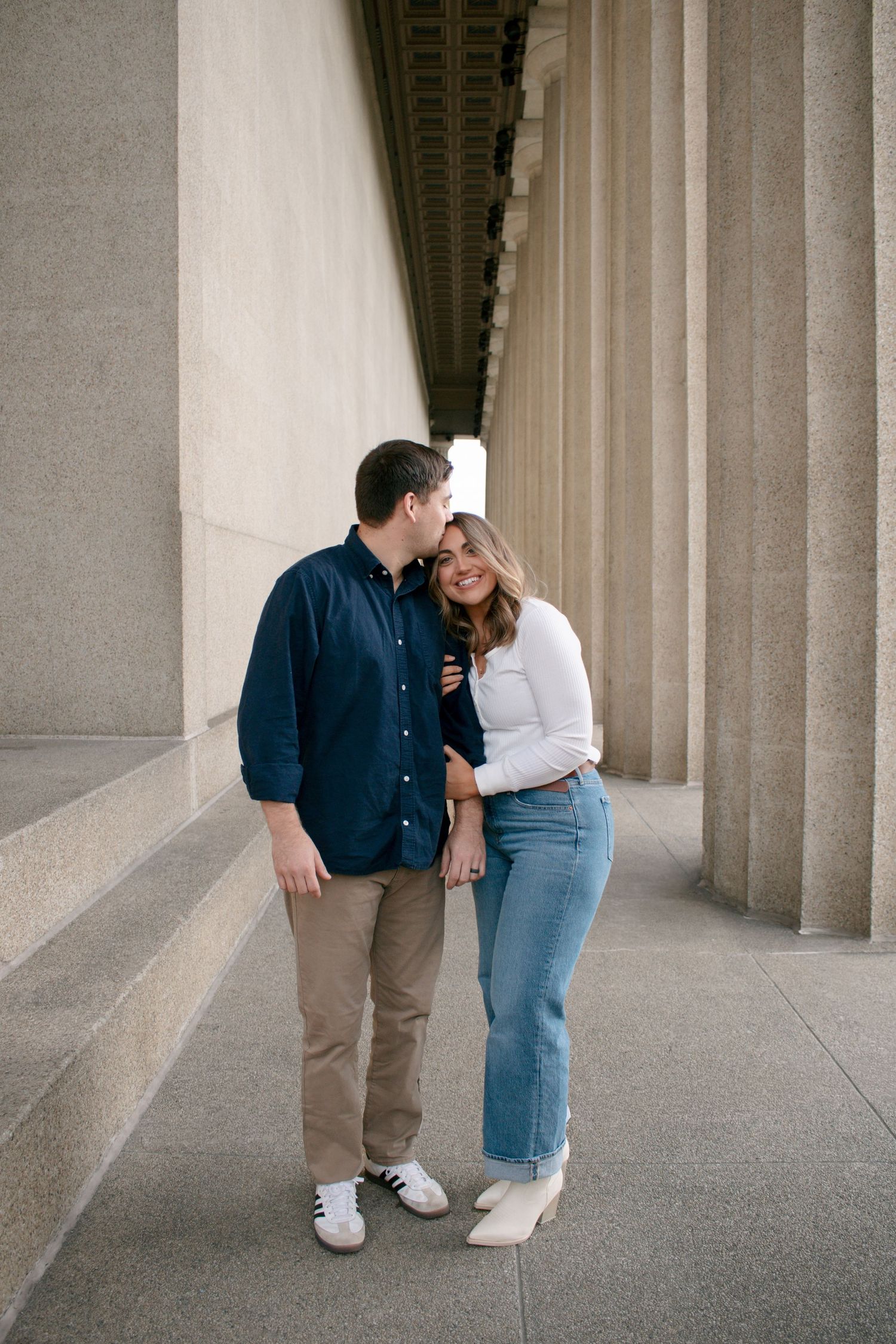 Romantic couple sharing an intimate moment between elegant stone pillars.