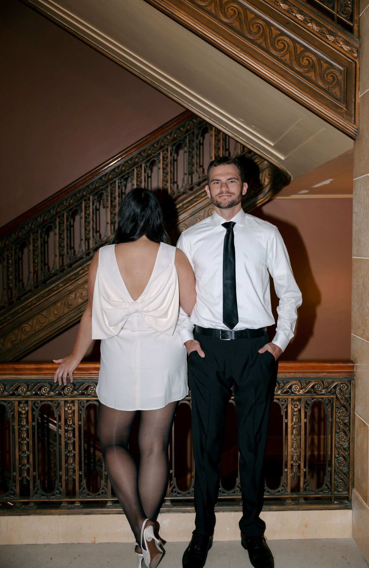 Two people in formal attire dance together on an ornate staircase in a vintage-style photo series.