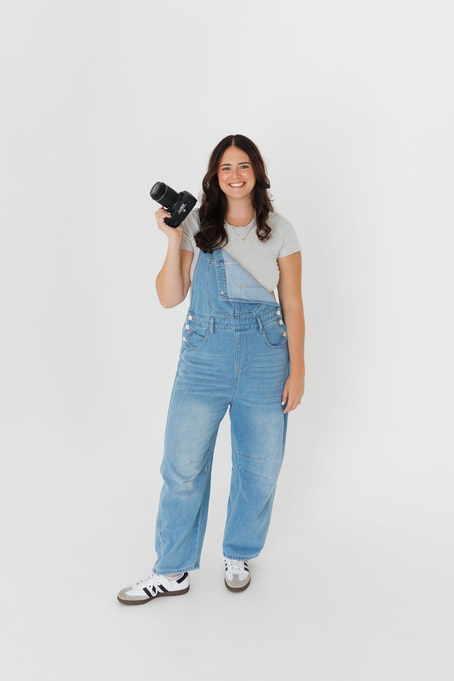 Series showing photographer in overalls posing with camera against white backdrop.