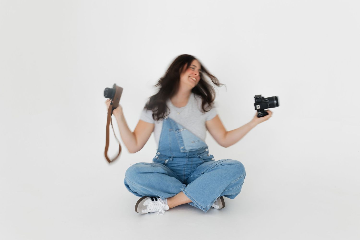 Playful photography session with denim overalls and camera on white background.