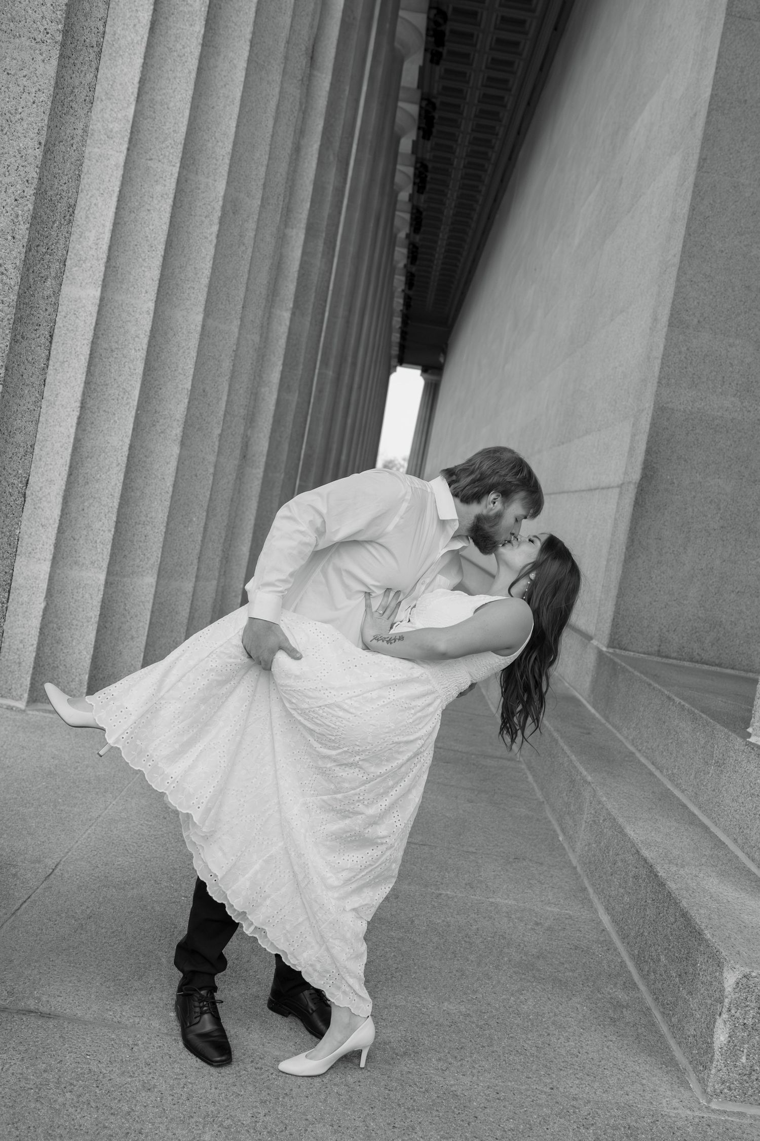 A series of black and white photos showing a dancer in a flowing white dress performing graceful movements between columns.