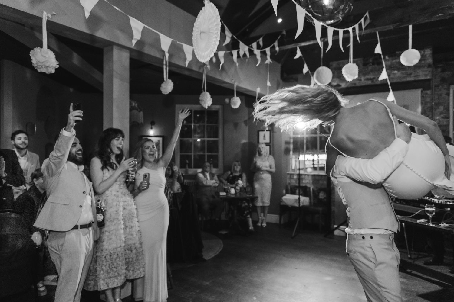 Wedding reception with white bunting decorations and guests dancing in black and white. Ephemera.