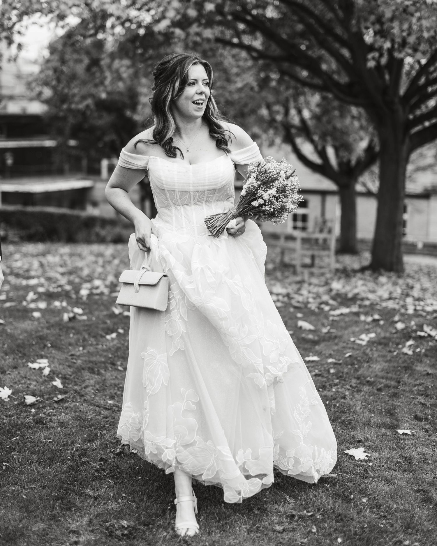 Black and white photo of someone in a flowing white wedding dress walking through autumn leaves. Ephemera.