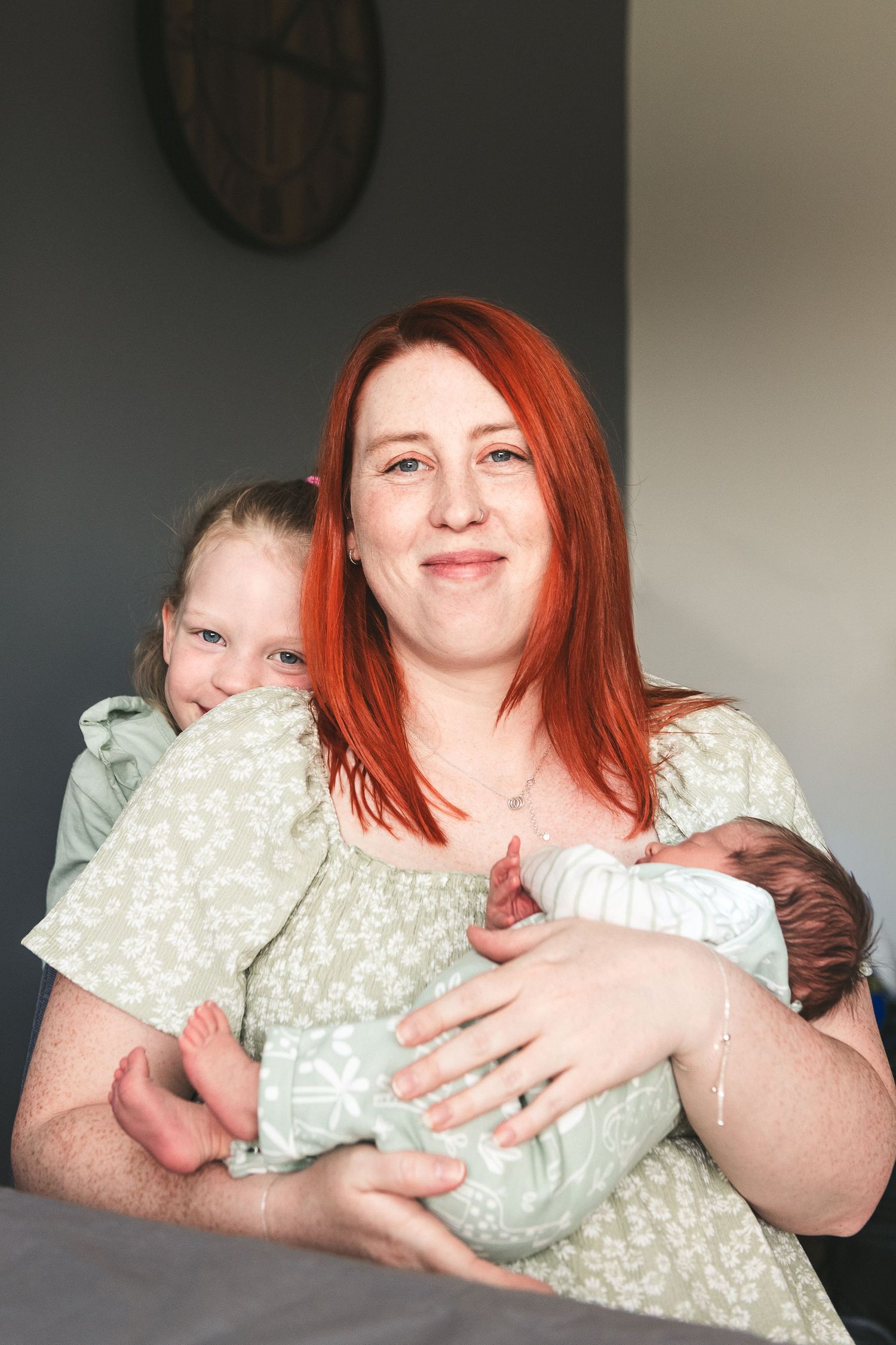 Mother and child share tender moment with newborn baby indoors. Ephemera.