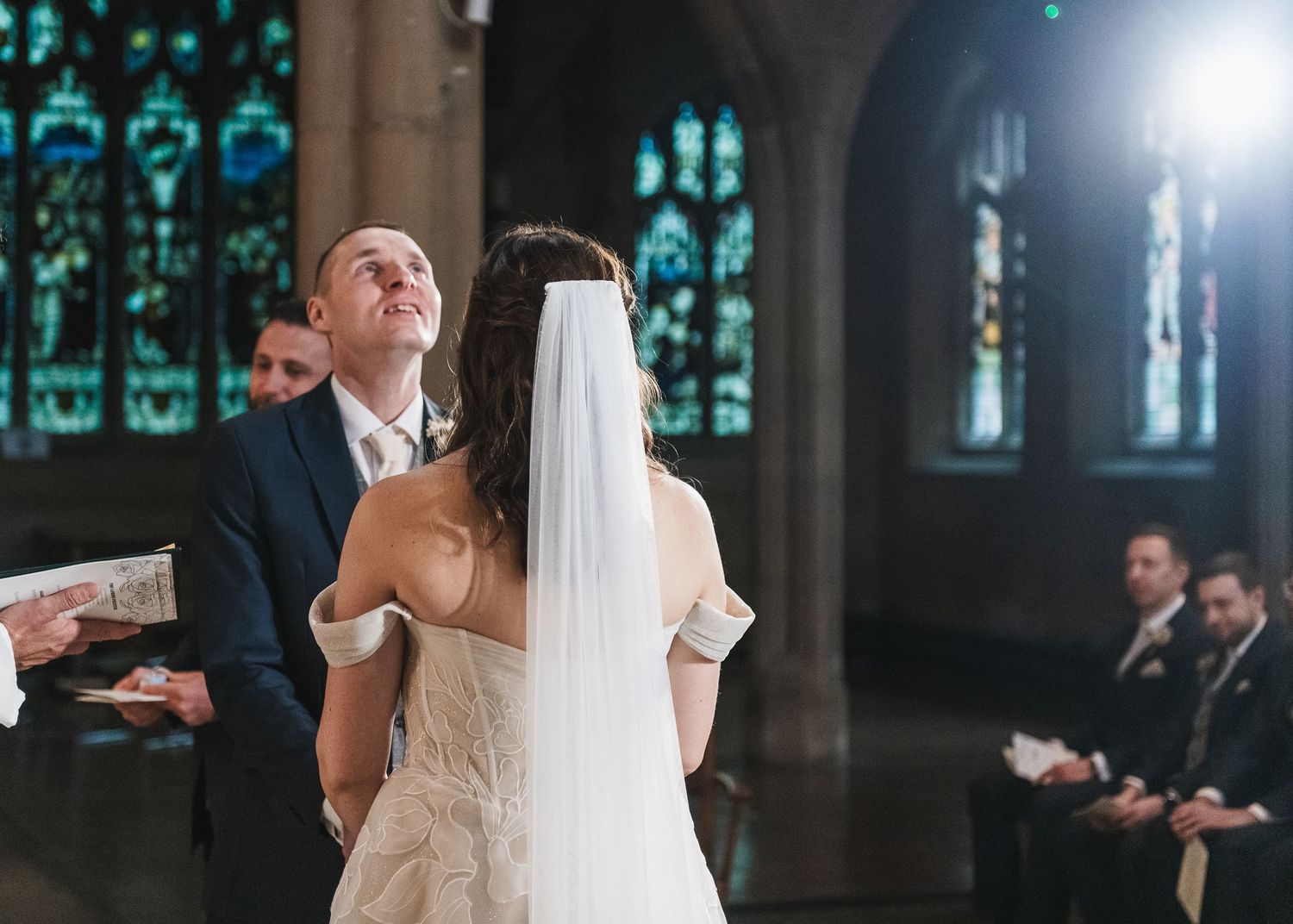 Wedding ceremony in a historic chapel with stained glass windows and dramatic lighting. Ephemera.