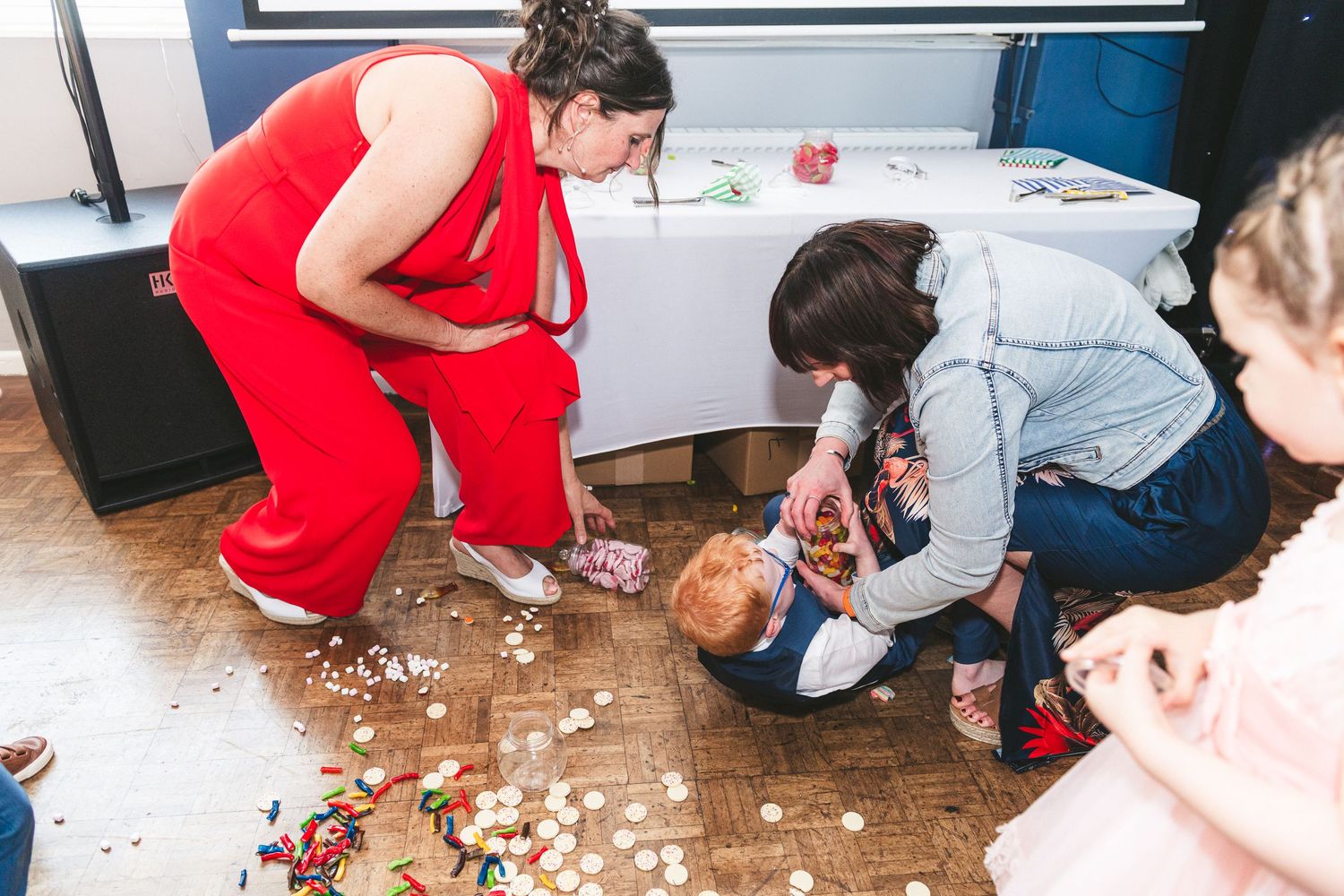 People gathered on the floor collecting scattered items at an indoor event. Ephemera.