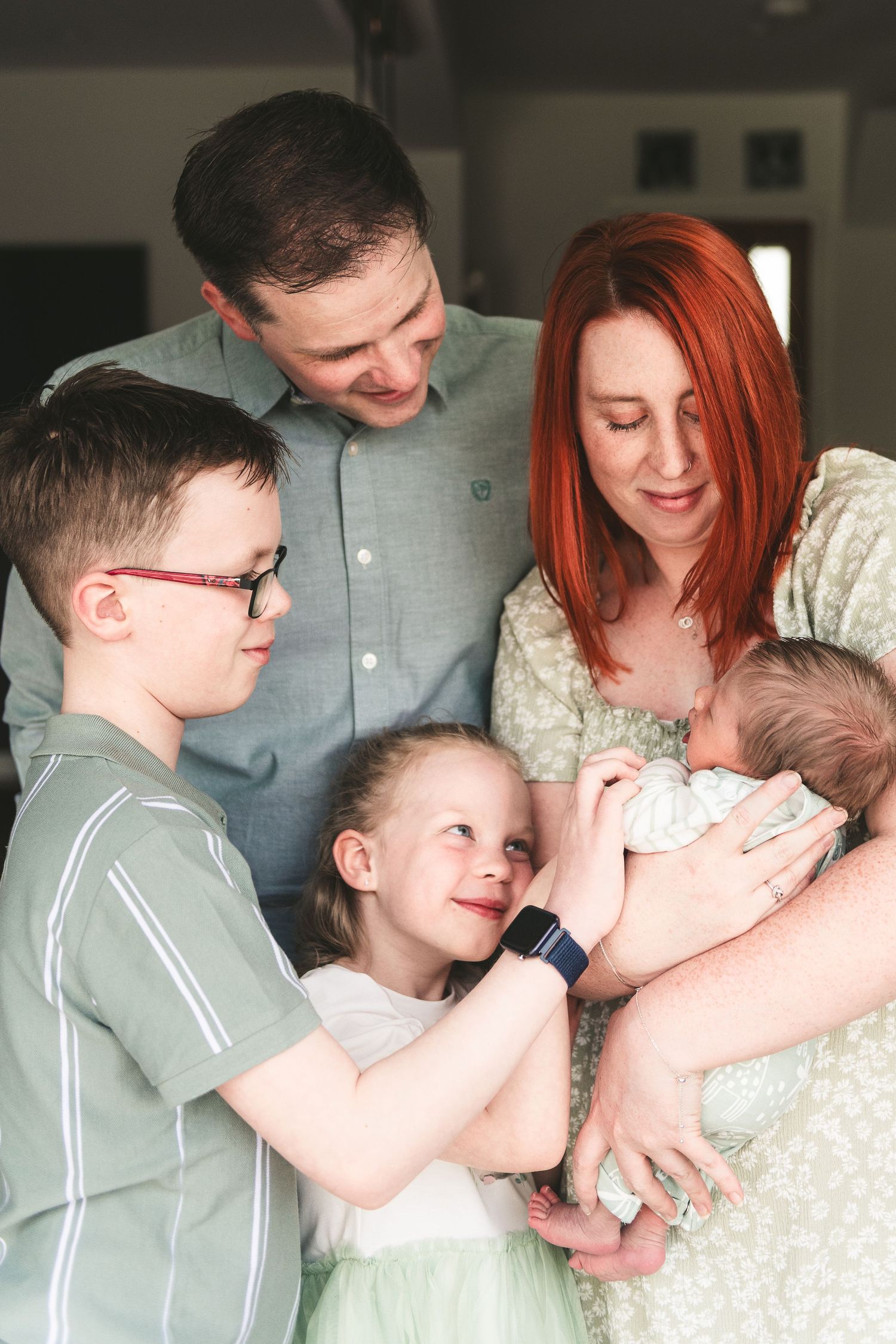 Family gathers around newborn baby in intimate indoor portrait. Ephemera.