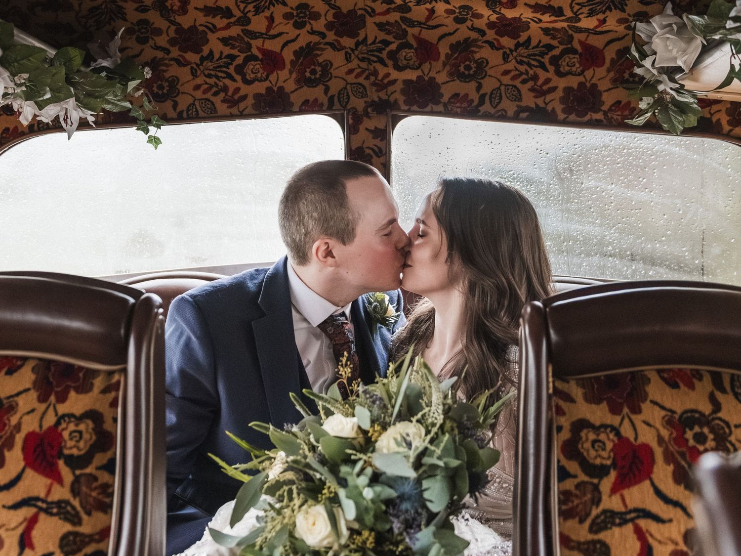 Romantic couple sharing an intimate moment against an ornate wallpaper backdrop during their wedding day.