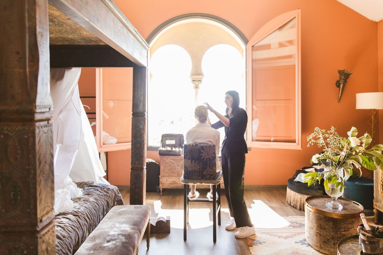 Getting ready moment: The makeup artist applies the bride's makeup in front of a sunny window.
