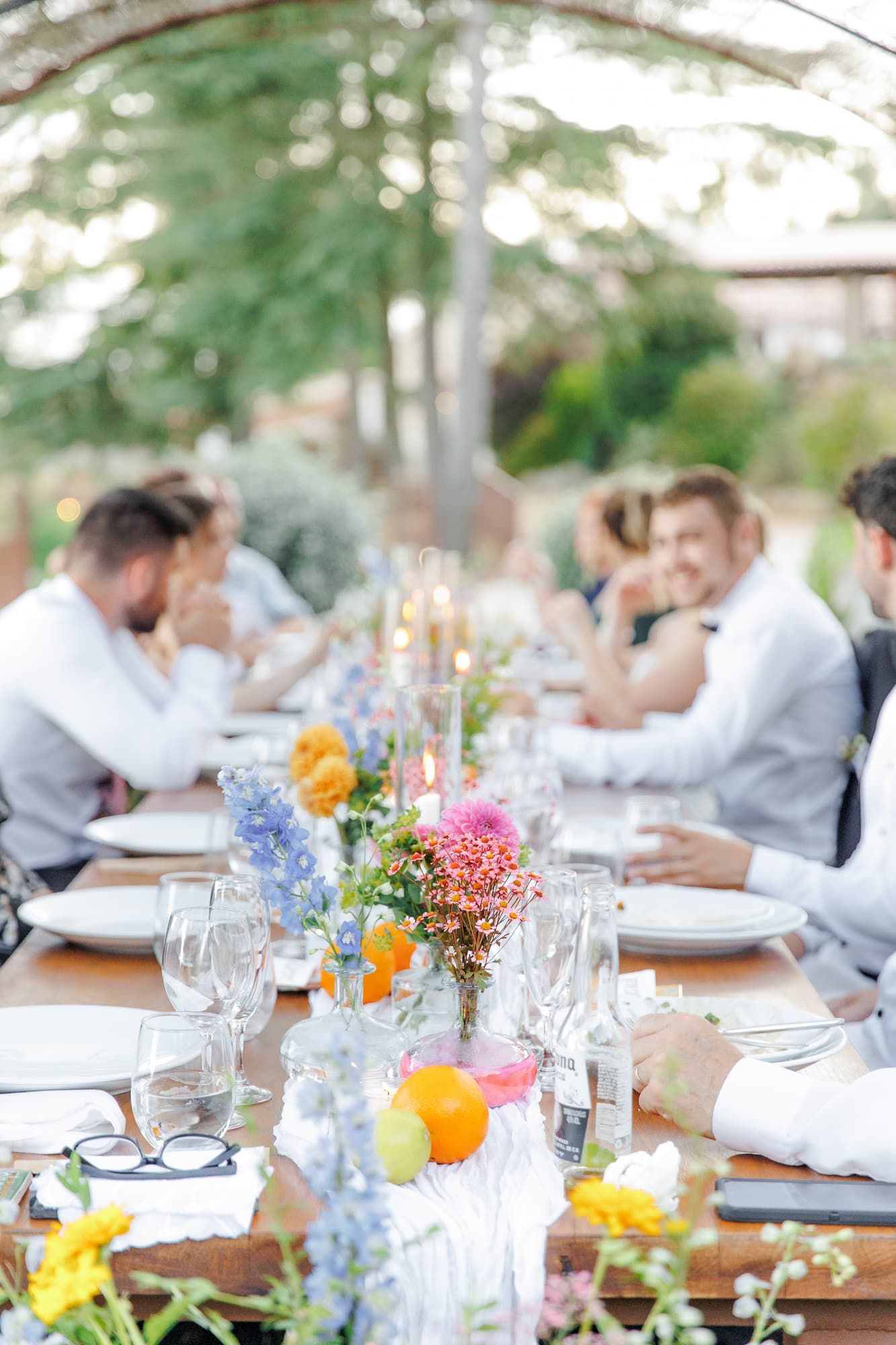 Elegant outdoor dining table decorated with colorful flowers and glassware for a garden wedding reception.