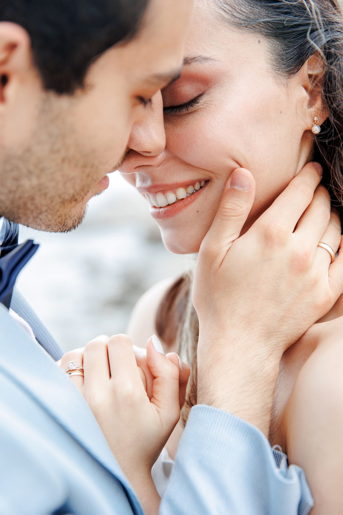 A romantic close-up photo of a couple sharing tender, intimate moments together against a light background.