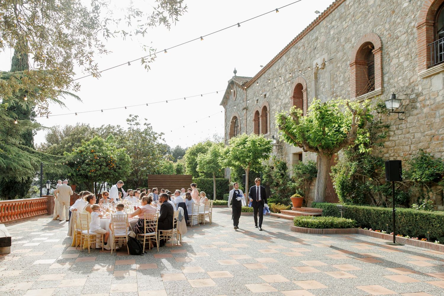 Elegant outdoor wedding reception at Mas de Sant Lleí with string lights, round tables, and lush greenery.