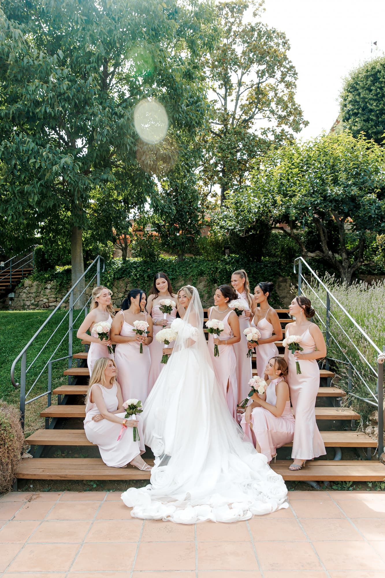 Bride in white gown poses with bridesmaids in pink dresses at the wedding venue Castell de Sant Marçal