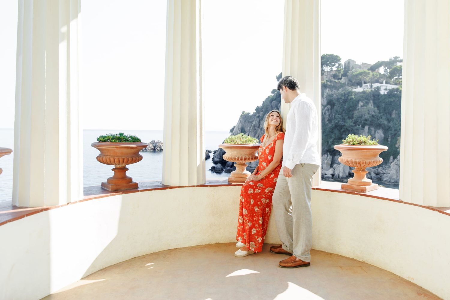 Couple in love sharing a tender moment on a scenic Amalfi Coast terrace with ocean views and terracotta planters.